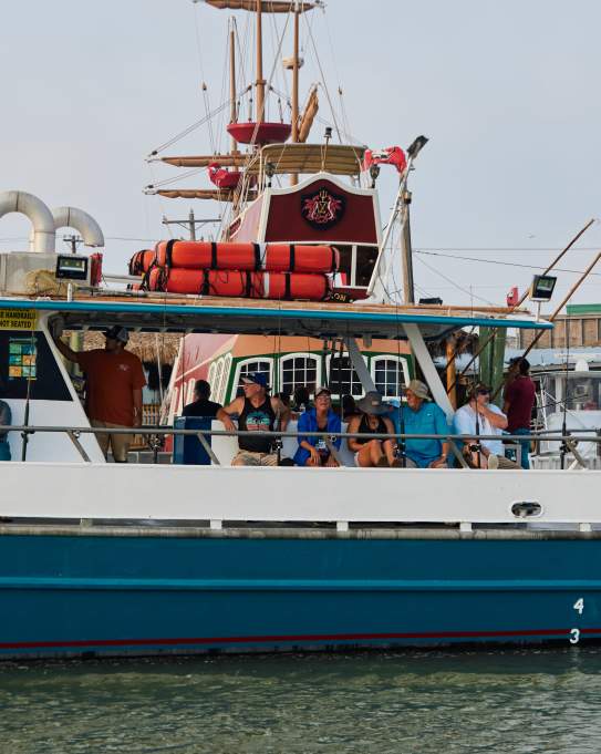 A group sits on a charter boat. Pirate ship is visible in background.