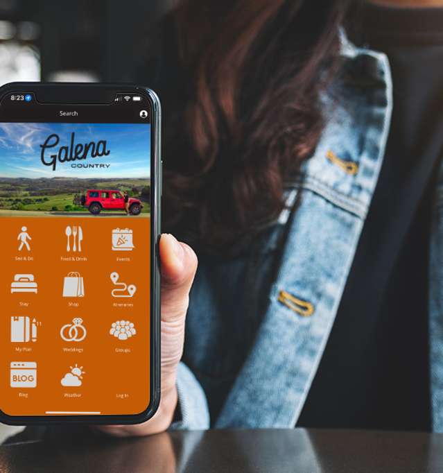 Person holding a phone, wearing a jean jacket.