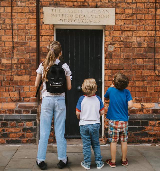 Three children looking at a historic mural on the side of a building in the Bailgate, lincoln.