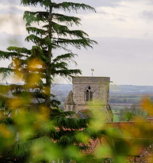 A church in the Lincolnshire Wolds with blurred trees in the foreground.