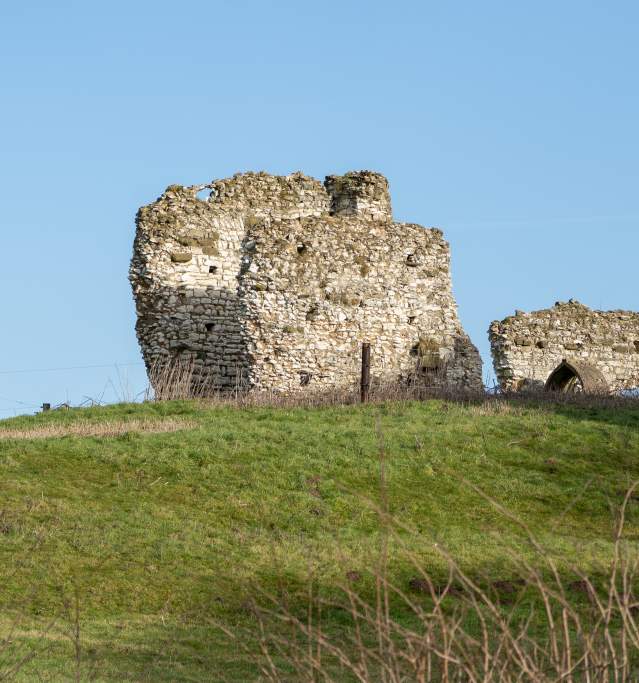 roman ruins on top of a grassy hill