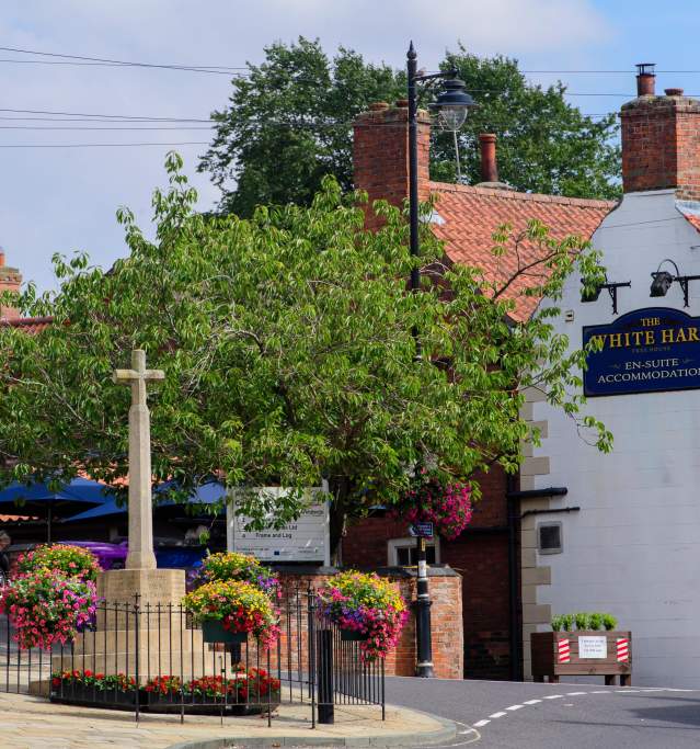 war memorial and country pub in street with flowers around it