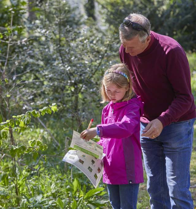 a man and child looking at a map by trees in countryside