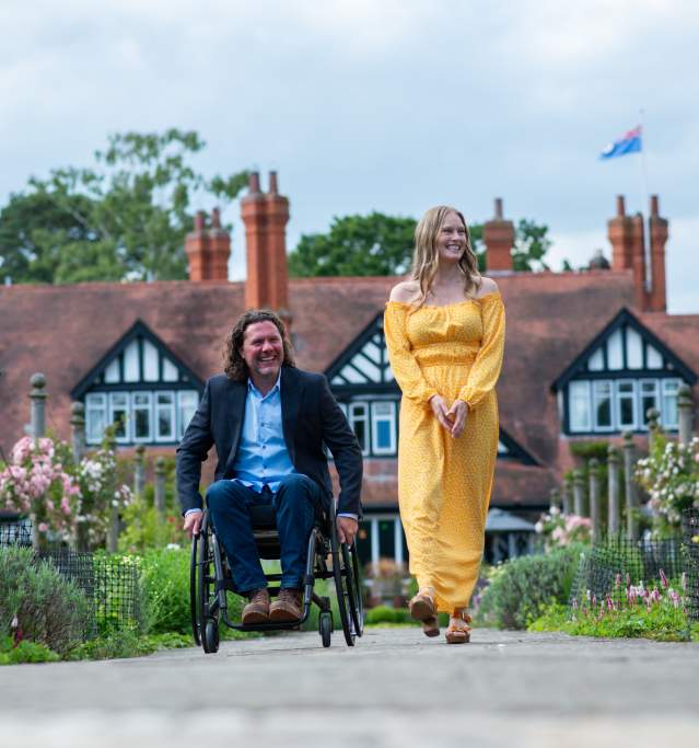 A man in a wheelchair explores the blooming gardens of the Petwood Hotel, with a woman by his side