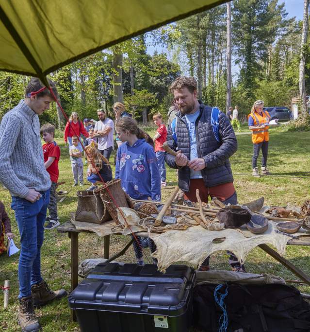 an outdoor festival with stand with people surrounded by trees and crafting
