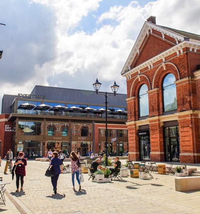 lively scene of Exchange Square in the Cornhill Quarter with people walking, shops in distance and clouds in the sky