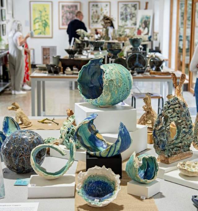 An exhibition space with pottery displays and people in background