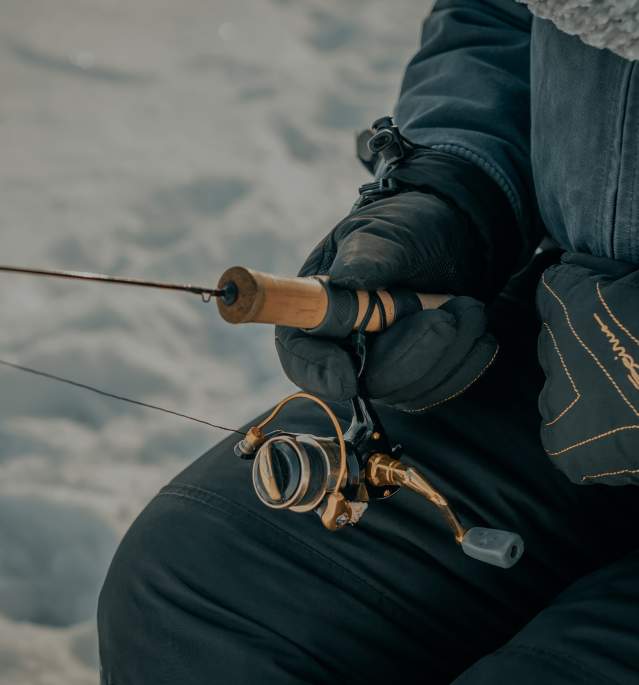 Close up of man holding rod while ice fishing