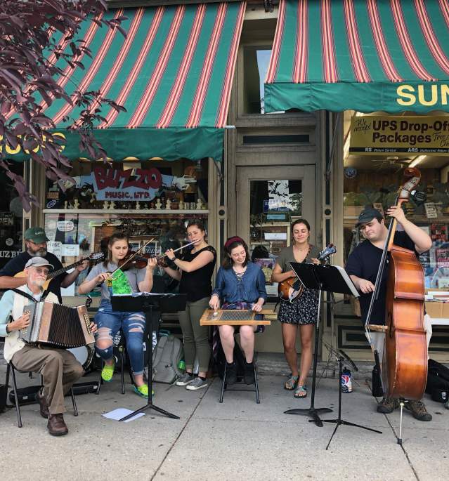 Seven people playing instruments outside store