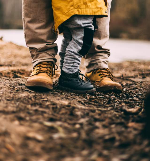 Close up of adult and child sneakers standing in the woods