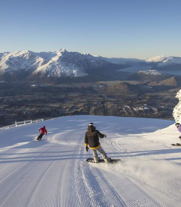 Snowboarders and skiers riding down snowy mountain