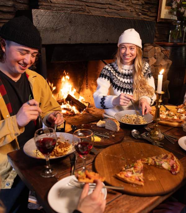 Group of friends eating at a cosy restaurant with fire roaring in the background