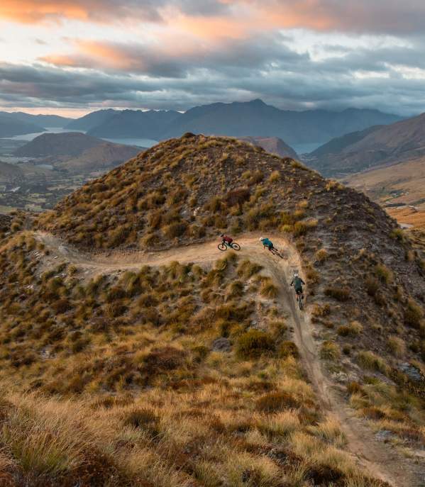 Mountain bikers riding at the top of a mountain with views of the basin in the background