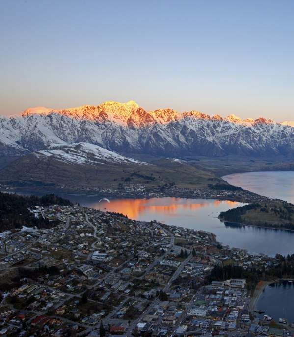 Aerial shot of Queenstown with snow capped mountains, lake and town