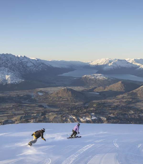 Skiers at Coronet Peak with wide view of snow-capped mountains