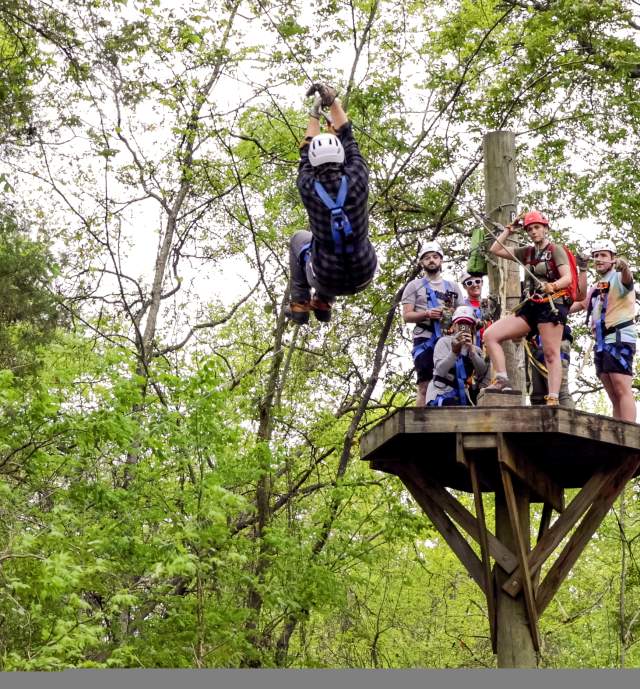 Young man ziplining through trees