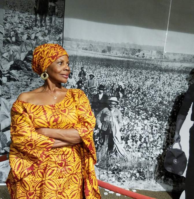Dr. Kitty Oliver standing in front of a black and white photo at the African American Research Library