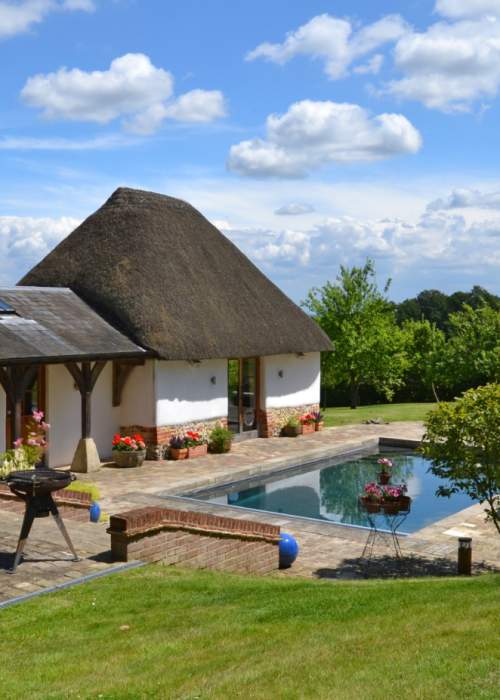 Self catering cottage exterior with garden, pool and barn in the New Forest