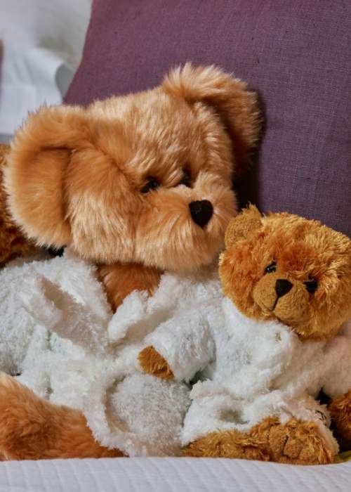 Family of teddy bears on the bed at luxury hotel in the New Forest