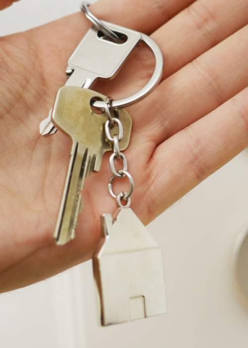 person's hand holding keys to new house in front of door