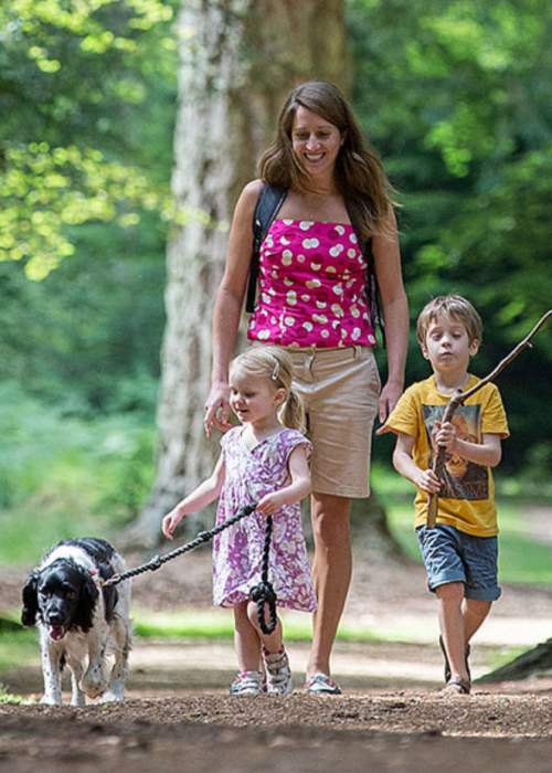 Family walking their dog through the woodlands in the New Forest