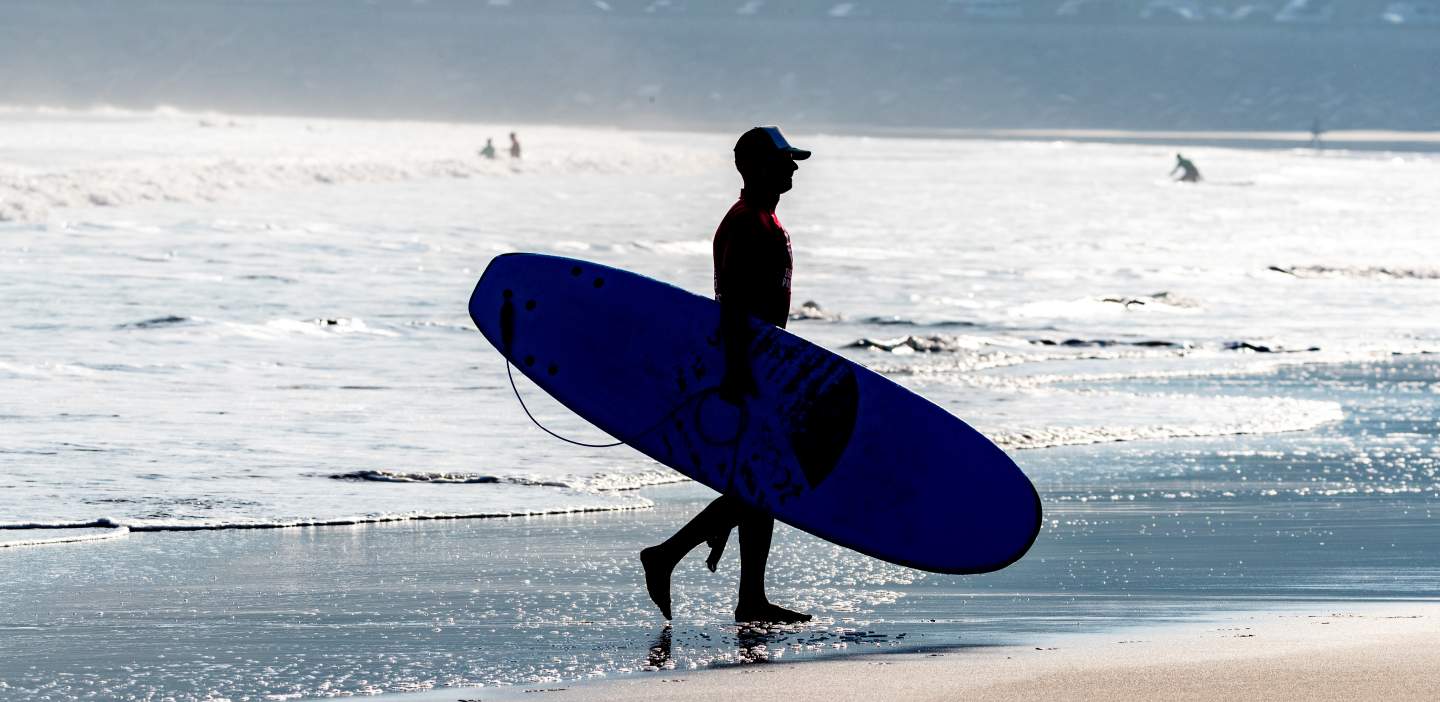An image of a surfer walking along seashore