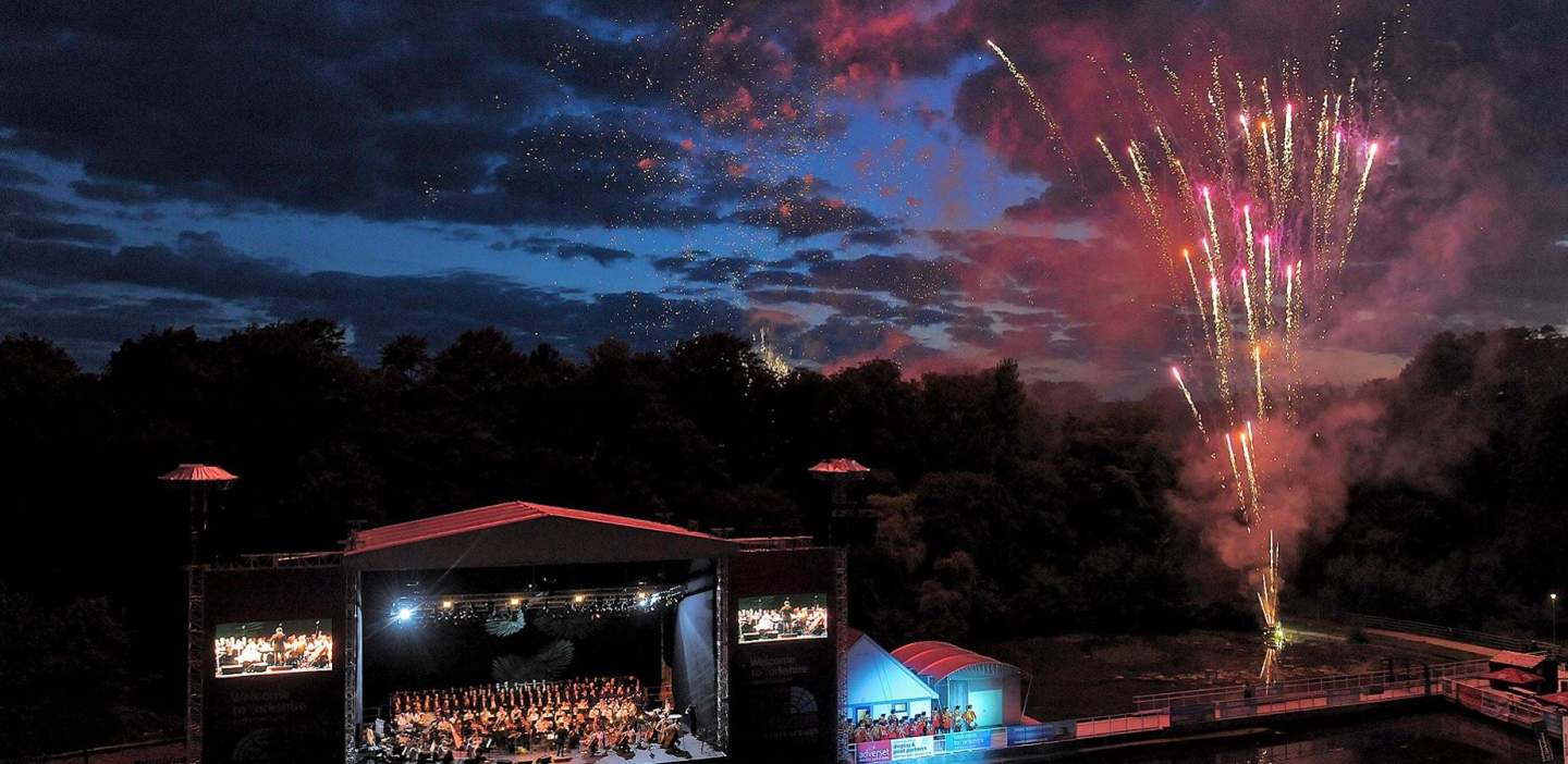 Outdoor theatre performance with fireworks in the background