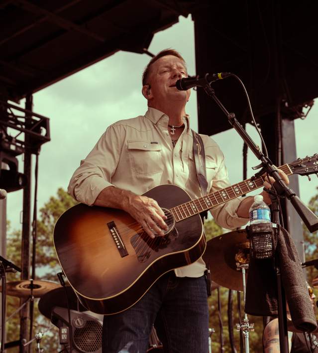 Man in country gear performing on a stage with a guitar