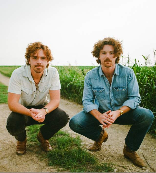 Briscoe band members crouch on a dirt road