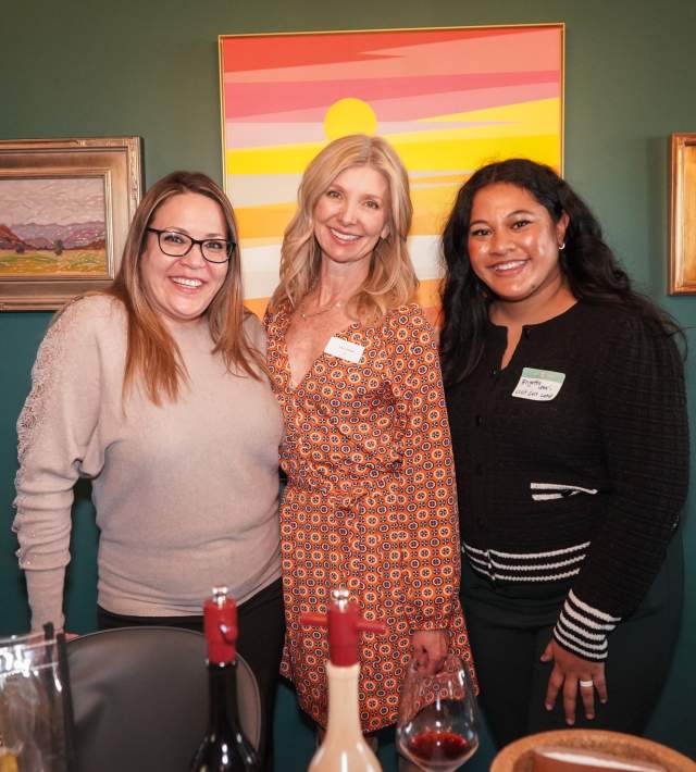 Three women standing close together and smiling