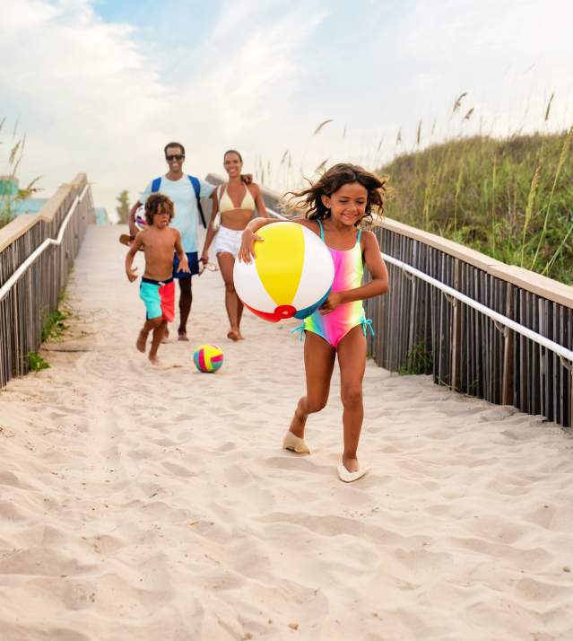 Family Running Down Beach Access Point