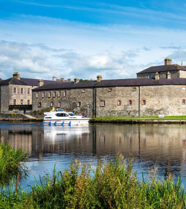 A cruiser going past the front of Enniskillen Castle on a sunny day.