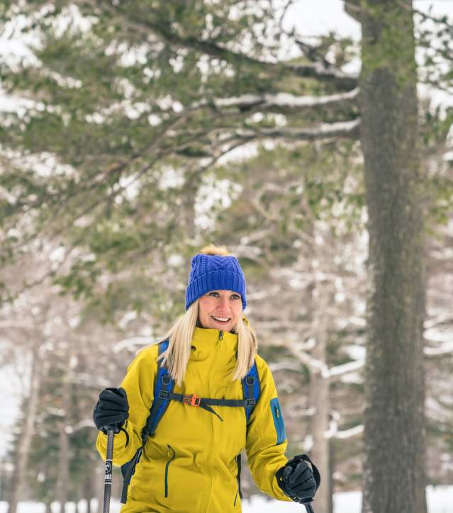 A woman snowshoes through the woods.