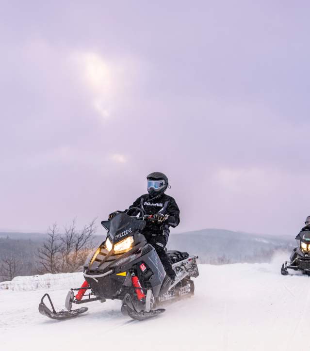 Two snowmobilers riding Brockway Mountain Trail.