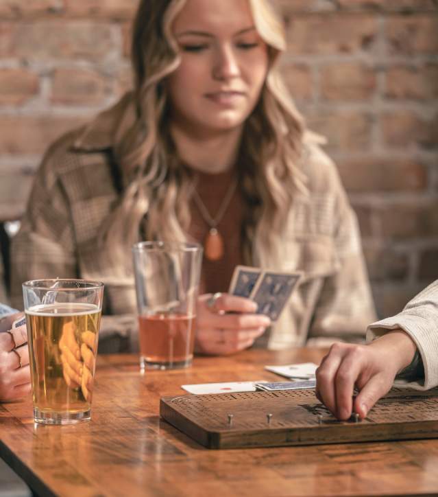 Girls enjoy pints of local beer and play a game of cribbage at a local brewery.