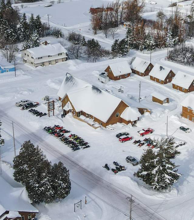 snowmobiles fill the parking lot of a snowy small lakeside town