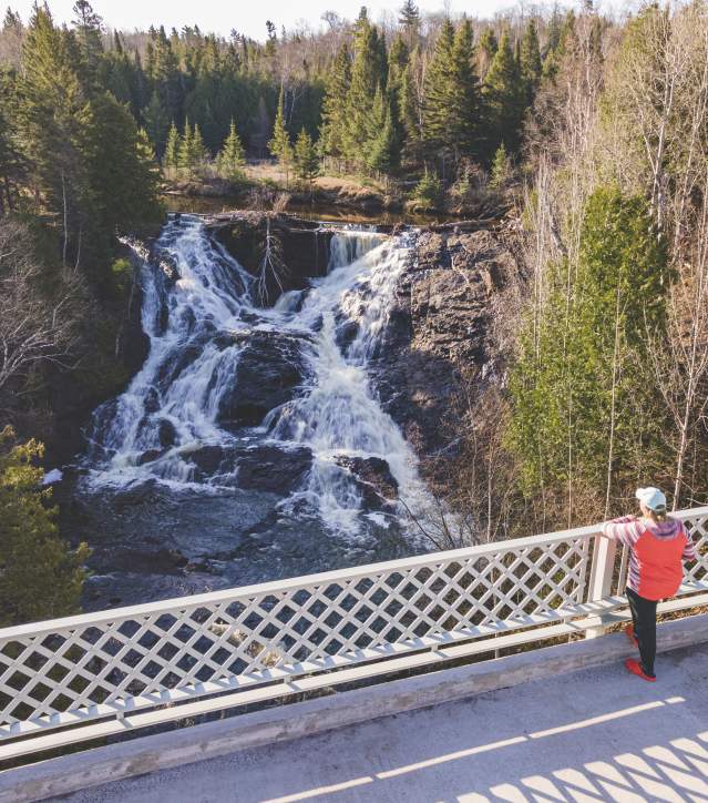 Person looks at Eagle River Falls from bridge.