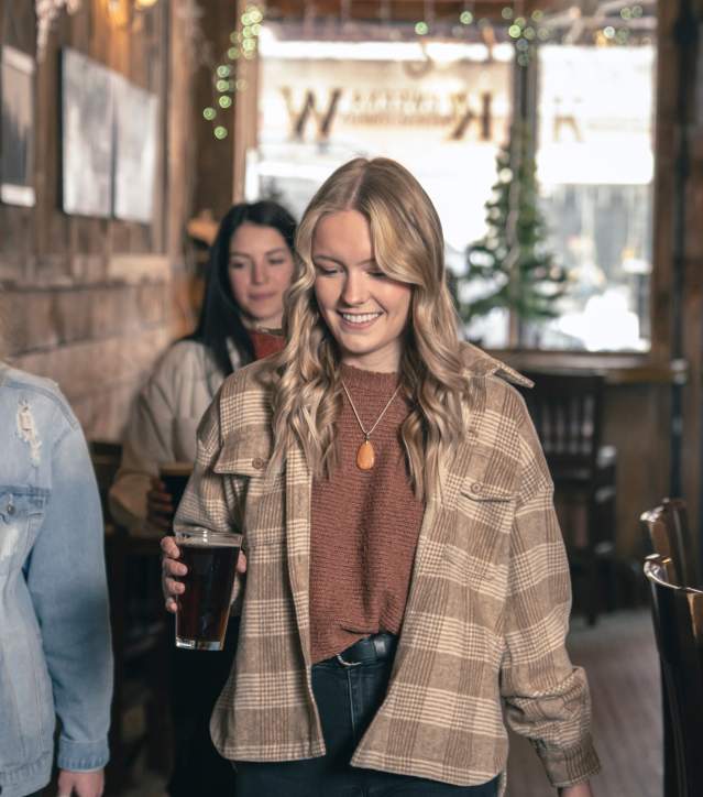 Three woman walking and holding beer in Taproom