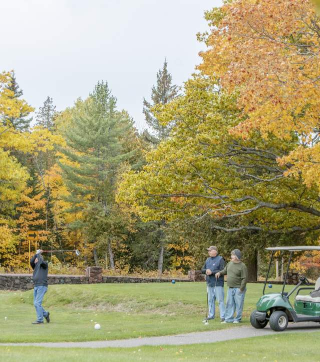 Golfers with golf carts enjoy a fall golf outing.