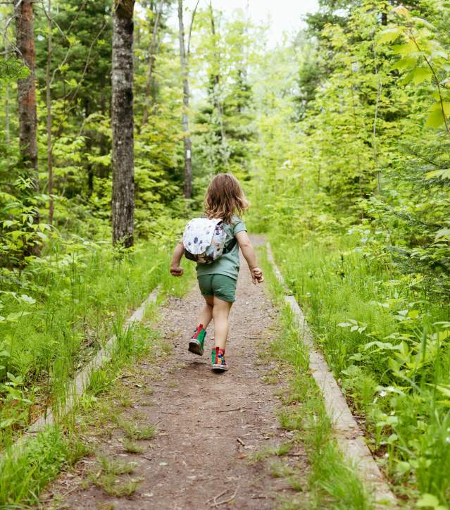 Young girl hiking through a forested trail.