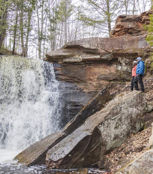 Man and woman stand on rocks overlooking Hungarian Falls in spring.