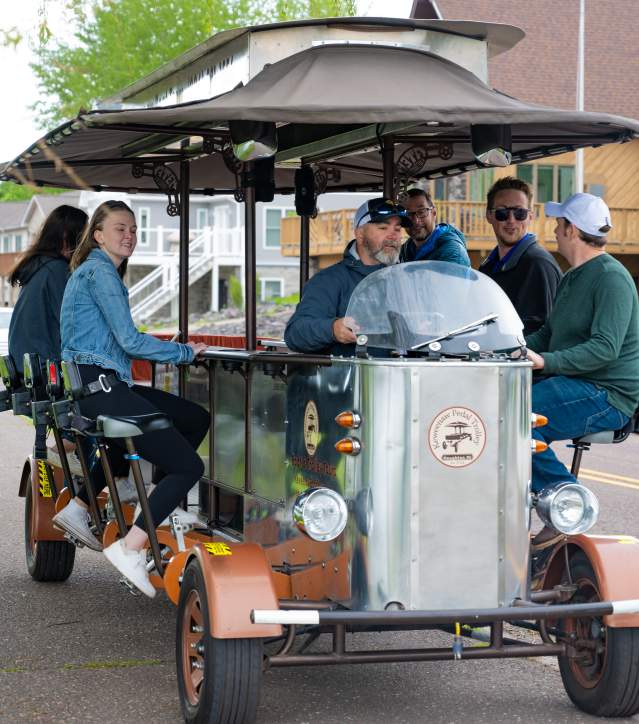 a pedal trolley with pedalling people cruises up a residential sidewalk