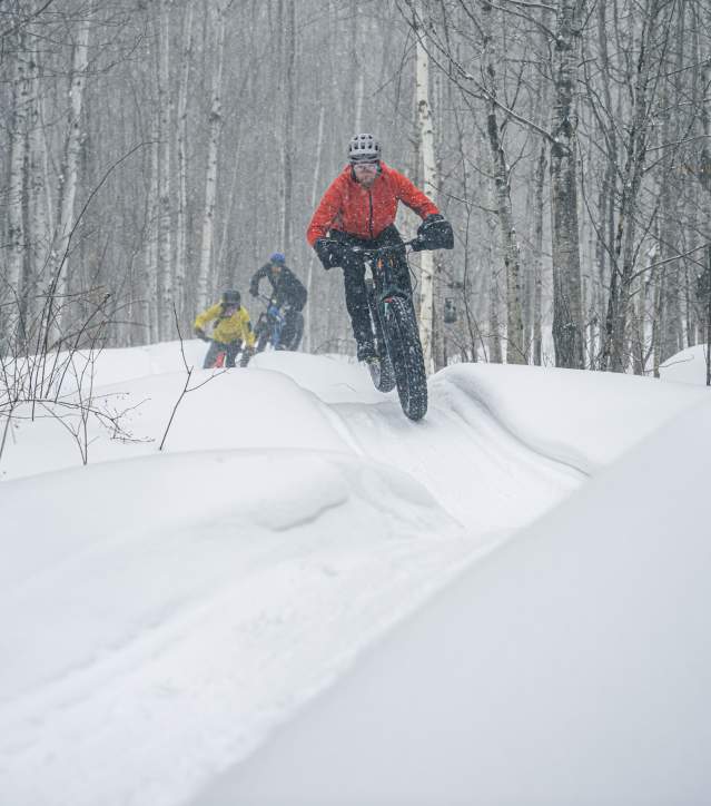 Fat-tire riders flowing over burms in the snow