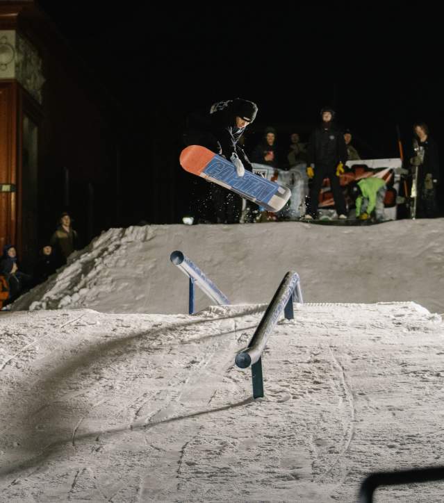 a snowboarder catches air in a downtown snow feature
