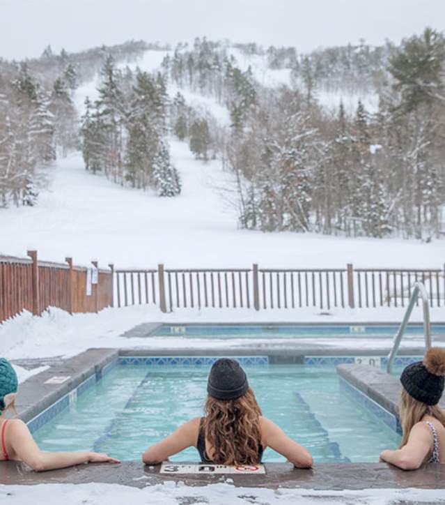 Three women relax at the nordic spa at Mount Bohemia