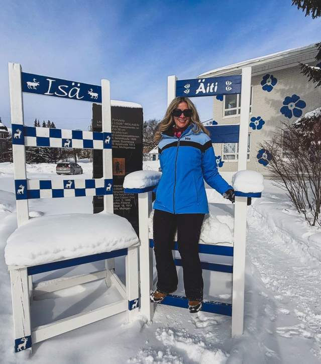 a person in snow gear stands on comically oversized chairs in the snow