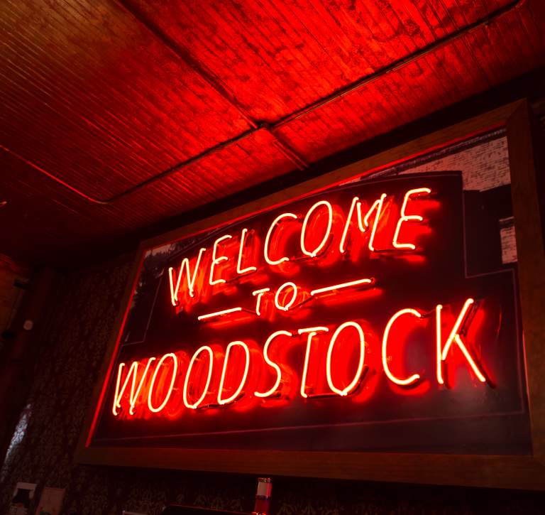 Neon Orange sign that says Welcome to Woodstock