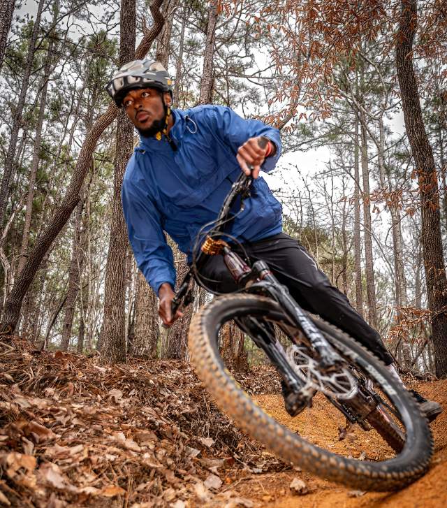 A mountain biker rounds the corner on a trail on a chilly day in the Fall.