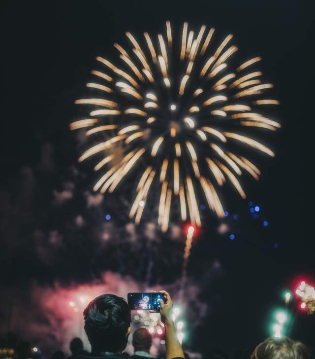 man taking a photo of fireworks
