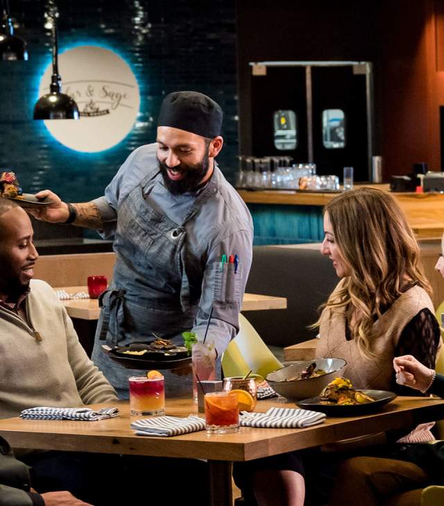 Chef serves a group of diners at Cedar and Sage restaurant in Green Bay.